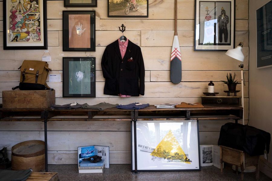 Plank-panelled wall with framed prints, a hanging jacket and an open shelf table